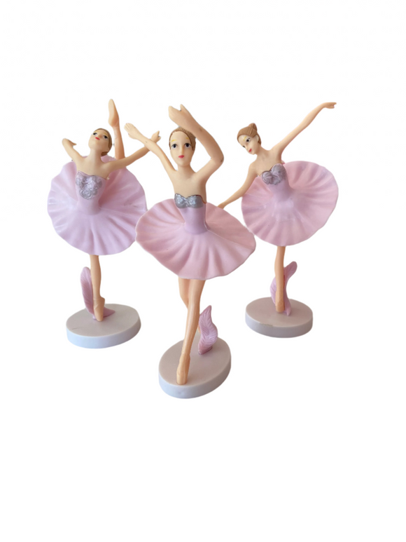 Three ballerina figurines in pink tutus on a white surface with a blurred background.