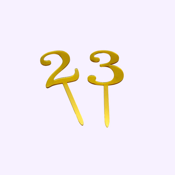 Two gold number cake toppers, '2' and '3', on a white background.