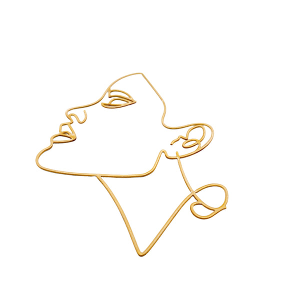 Gold wire sculpture of a face on a white background