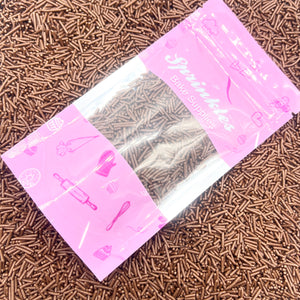 Pink packaging of chocolate sprinkles on a bed of chocolate sprinkles