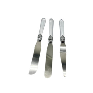 Three silver butter knives with decorative handles on a light gray background